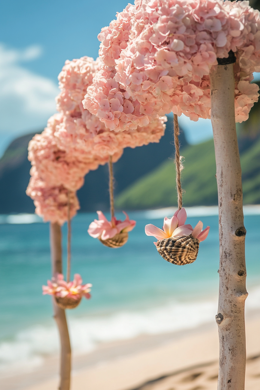 Wedding beach setup. Pale pink hydrangeas on a seashell arch, tiki torches and floating plumerias.