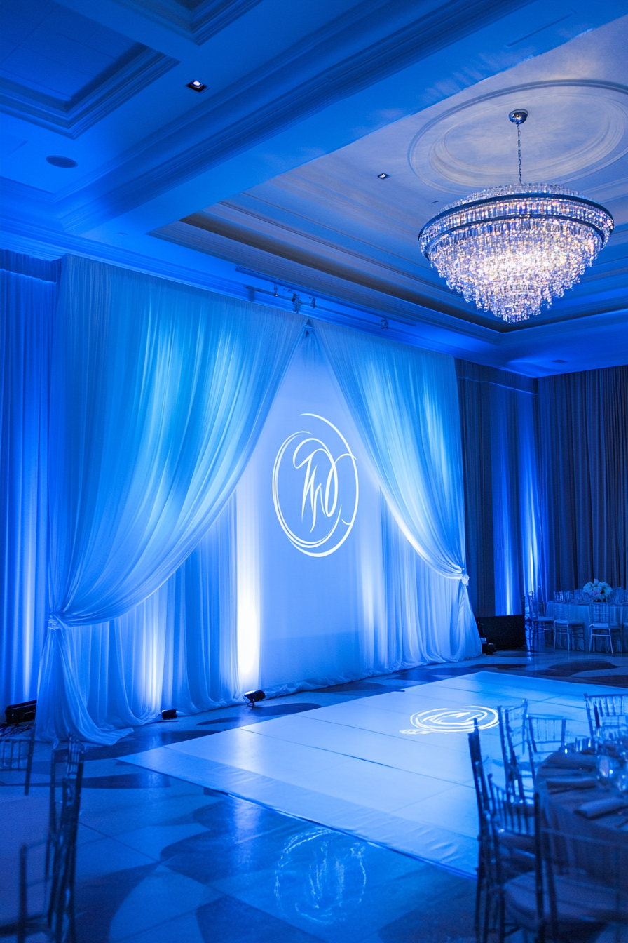 Wedding entertainment space. Monogram projection onto draped chiffon backdrop with blue LED hemisphere lightings.